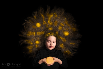 Zdjęcie wykonałam do tematu fotografii kreacyjnej podczas nauki na II semestrze Uniwersytetu AFD. Laura położyła się na podłodze i wcieliła się w rolę Słońca, a ja stanęłam z aparatem na drabinie, aby sfotografować ją z góry. Na jej włosach rozsypałam złoty brokat dla uzyskania takiego efektu.